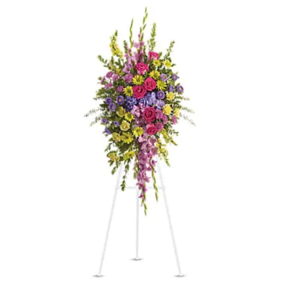 Tall standing floral spray with pink, purple, and yellow flowers on a white easel