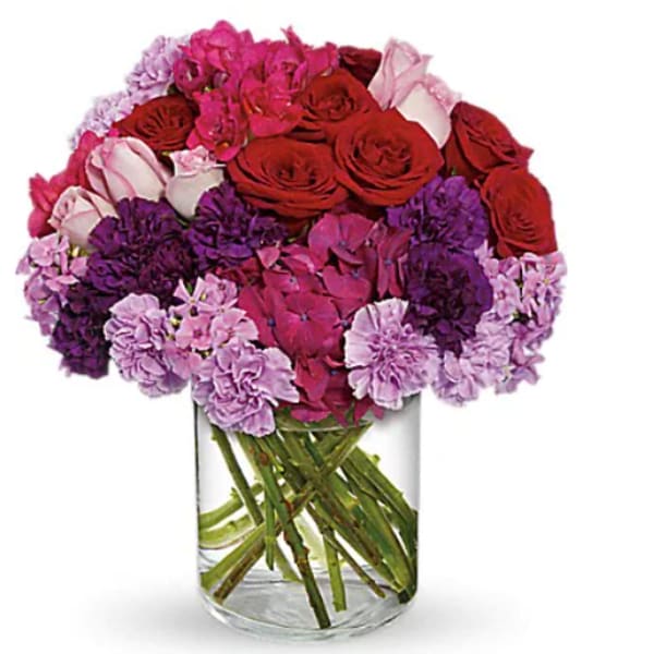 Bouquet of red, pink, and purple flowers in a clear glass vase