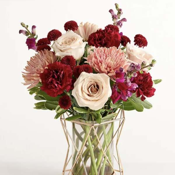 Mixed bouquet of roses, carnations, and chrysanthemums in a glass vase