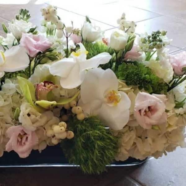 Low floral centerpiece with white orchids, hydrangeas, and pale pink blooms