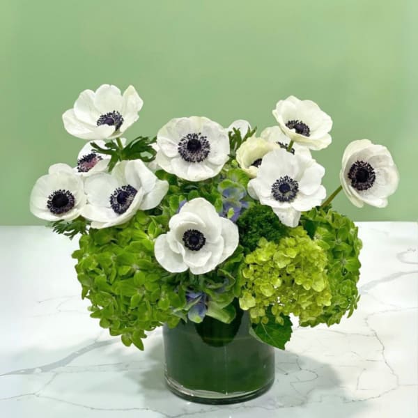 White anemones in a glass vase with bright green hydrangeas
