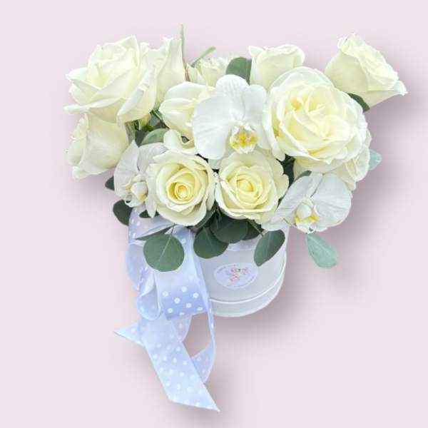 White roses and orchids in a white hatbox with a blue ribbon