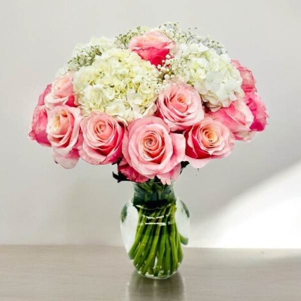 Pink roses and white hydrangeas arranged in a clear glass vase