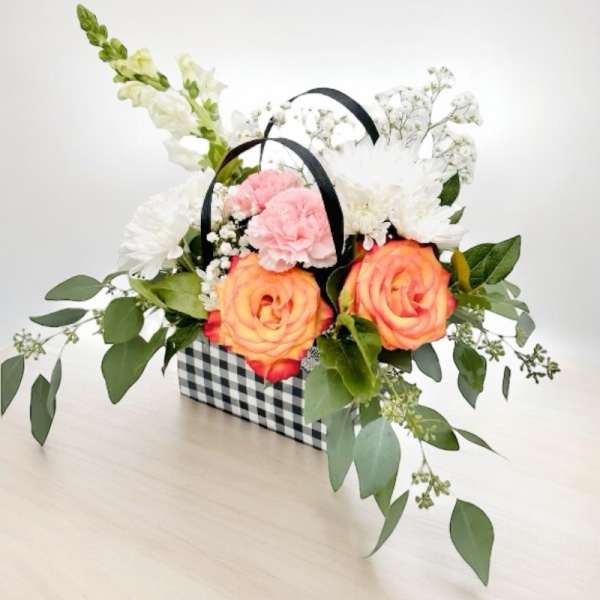 Basket arrangement with peach roses, pink carnations, and white flowers