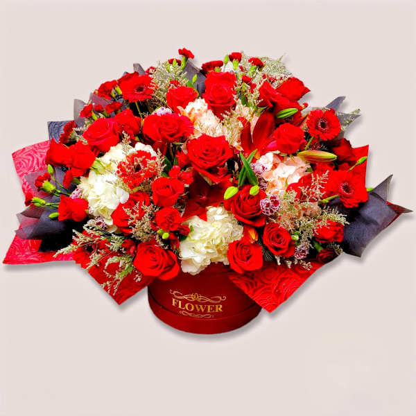 Red roses and white hydrangeas arranged in a round gift box