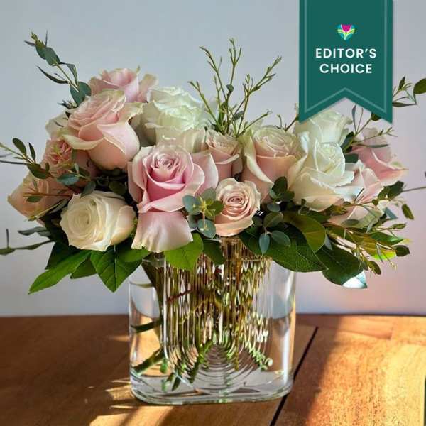 Pink and white roses arranged in a clear glass vase