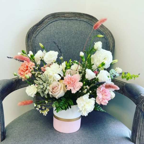Mixed bouquet of white and blush flowers in a pink-and-white box.