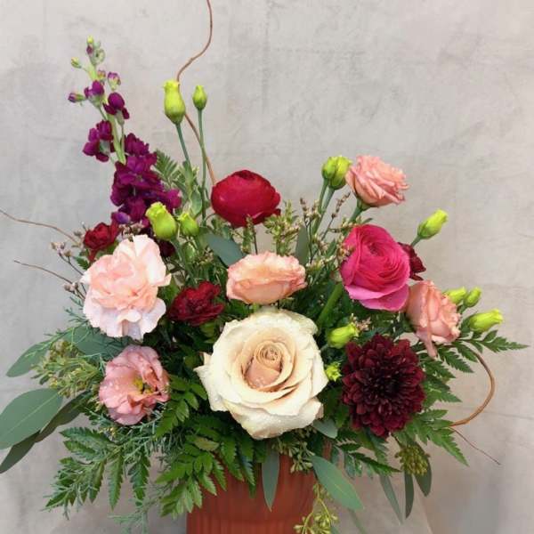 Mixed pink, cream, and burgundy flowers in a terracotta vase