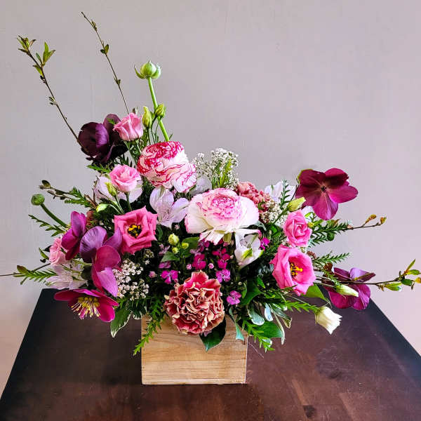 Asymmetrical pink and white flower arrangement with roses and lisianthus in a wooden box