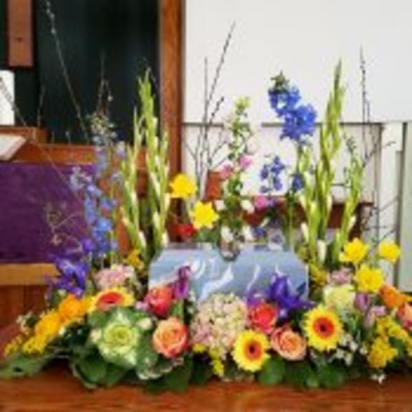 Colorful spring flower arrangement surrounding a decorative box on a wooden surface