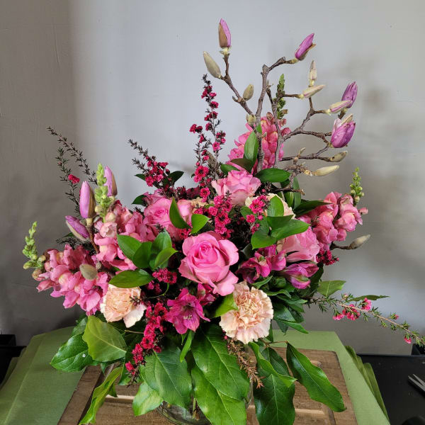 Tall pink rose and snapdragon arrangement with peach carnations in a clear glass vase