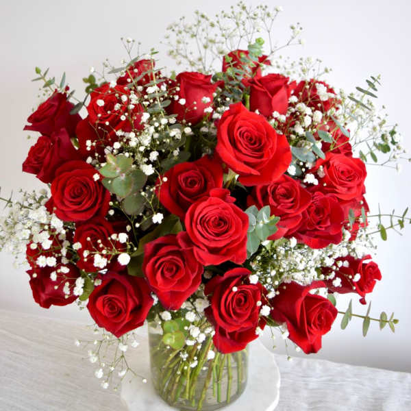 Bouquet of red roses with baby's breath in a clear glass vase