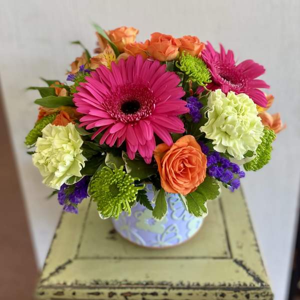 Bright mixed bouquet in a patterned vase with pink gerberas and orange roses