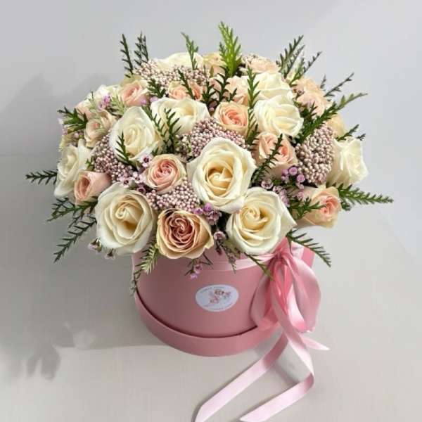 Bouquet of cream and blush roses in a pink hatbox with ribbon