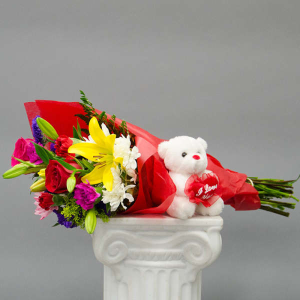 Bouquet of mixed flowers with a white teddy bear in red wrapping