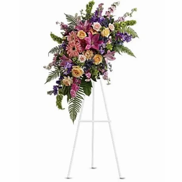 Standing floral spray with pink, purple, and peach flowers on a white easel