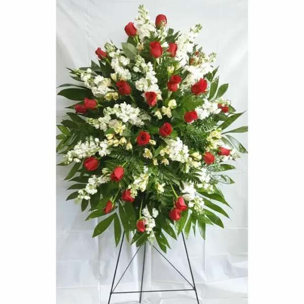 Standing spray of red roses and white flowers on a metal easel