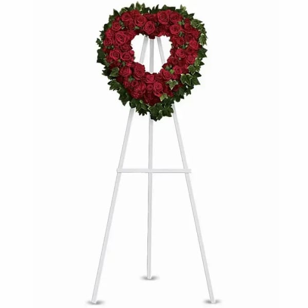 Heart-shaped red rose wreath on a white easel stand