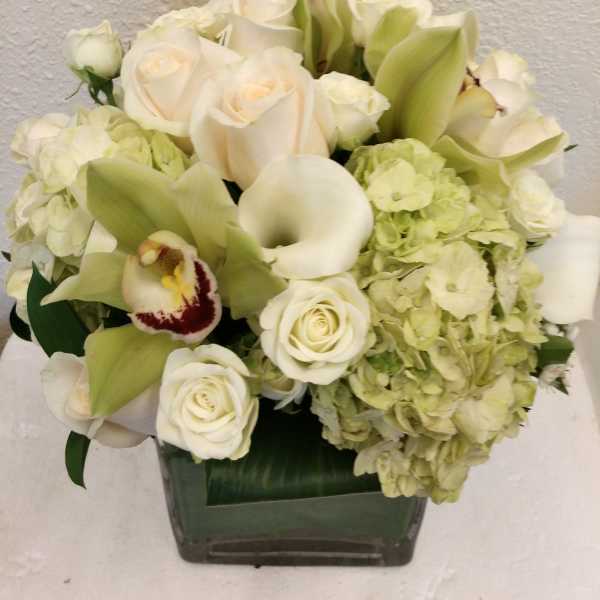White roses, calla lilies, and hydrangeas in a square vase