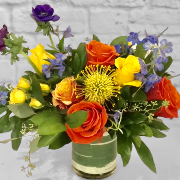 Colorful bouquet of roses and blue flowers in a glass vase