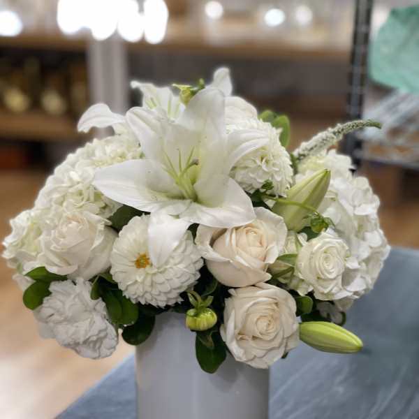 White lilies and roses arranged in a gray vase