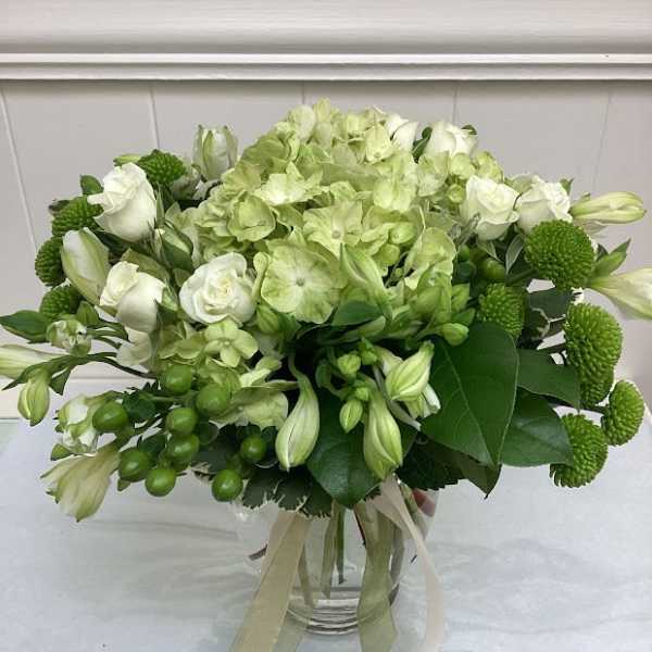 Green and white bouquet in a glass vase with ribbon