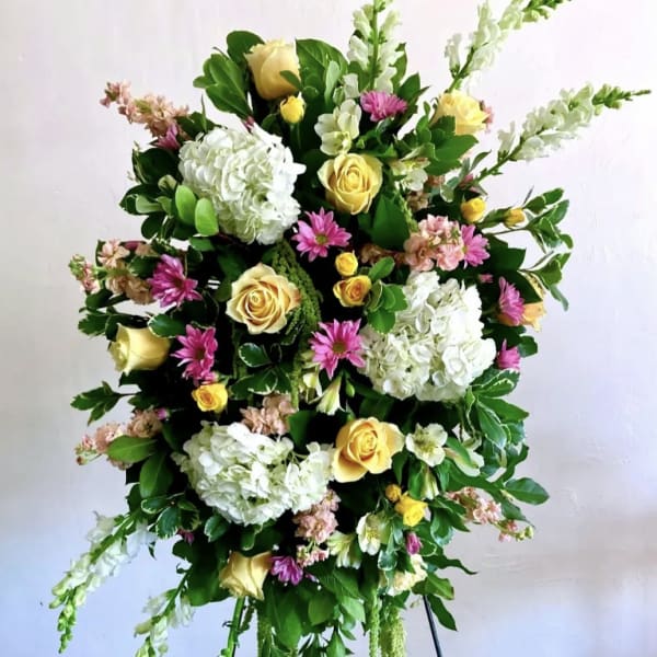 Tall floral spray with white hydrangeas, yellow roses, and pink daisies