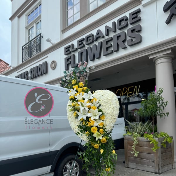 Standing floral heart arrangement with white blooms and yellow roses on an easel