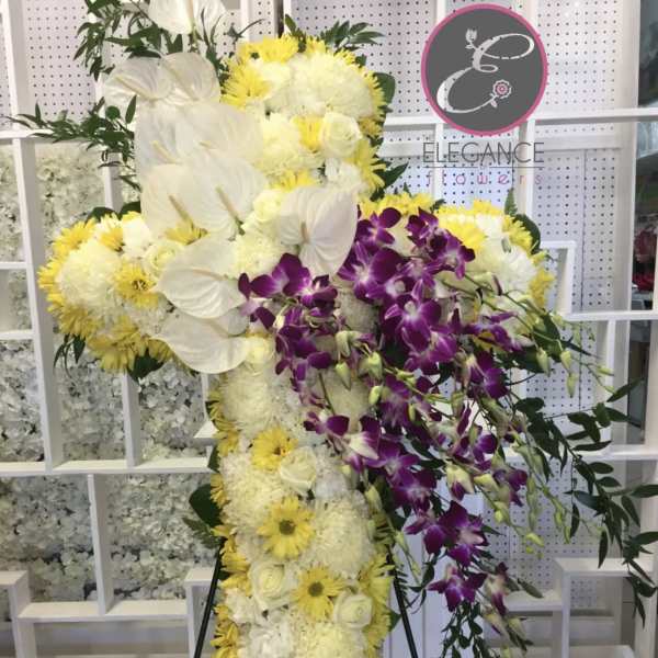 Standing floral cross with white and yellow flowers and purple orchids