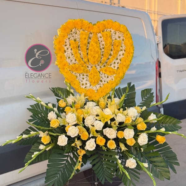 Heart-shaped yellow and white floral tribute on a stand with roses below