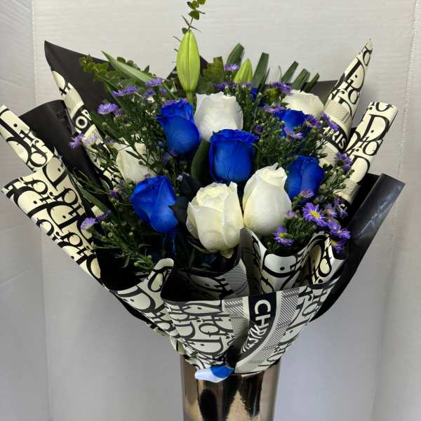 Bouquet of blue and white roses in a tall metallic vase