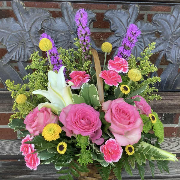 Basket arrangement with pink roses, white lilies, and yellow accents