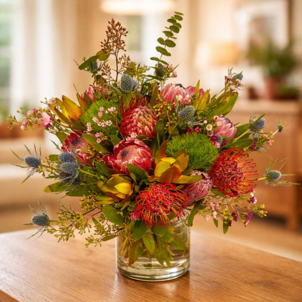 Mixed bouquet of pink and red flowers in a clear glass vase