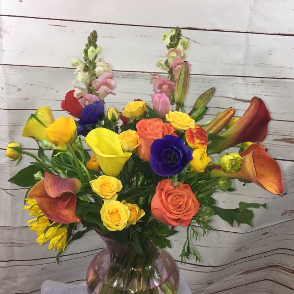 Mixed bouquet with roses, calla lilies, and snapdragons in a glass vase