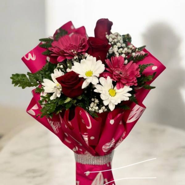 Bouquet of red roses, pink gerbera daisies, and white daisies wrapped in bright pink paper