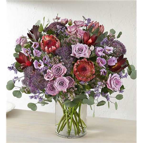 Lavender roses and purple flowers in a clear glass vase