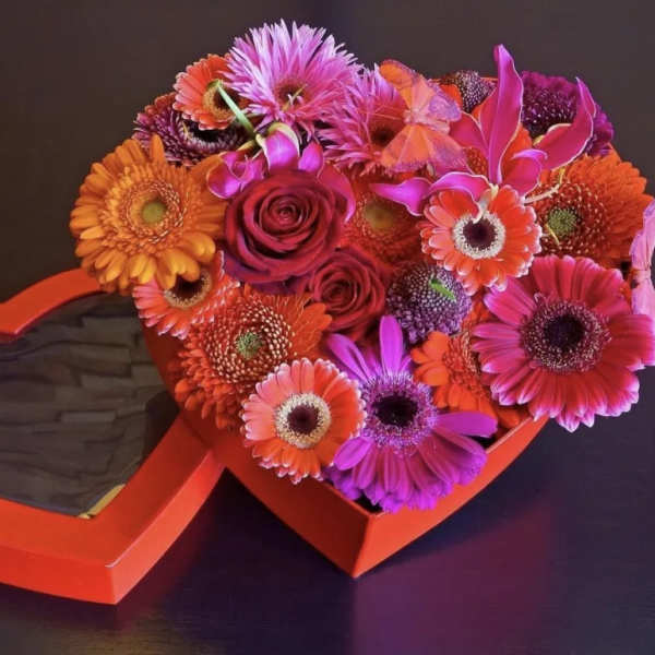 Heart-shaped box with bright mixed flowers and a red rose