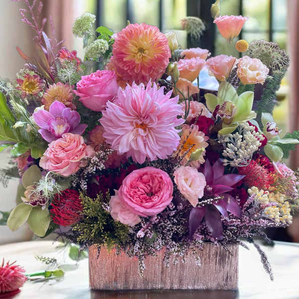 Pink and peach mixed flower arrangement in a square vase