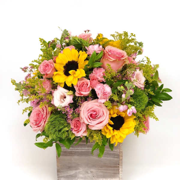 Pink roses and sunflowers in a wooden box