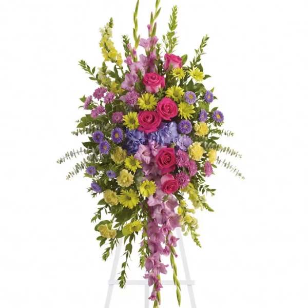 Tall standing spray of pink, yellow, and purple flowers on a white easel