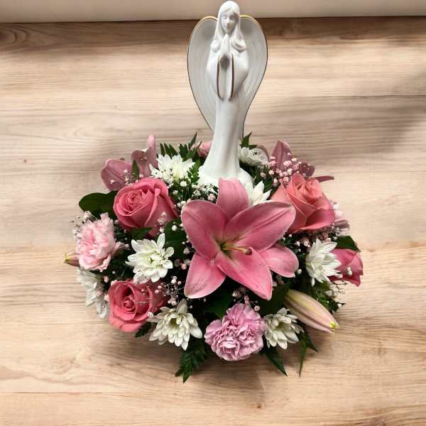 Low pink and white flower arrangement with a white angel figurine in the center