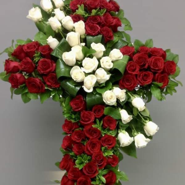 Cross-shaped arrangement of red and white roses on a neutral background