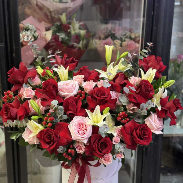 Large bouquet of red and pink roses with white lilies in a white hat box