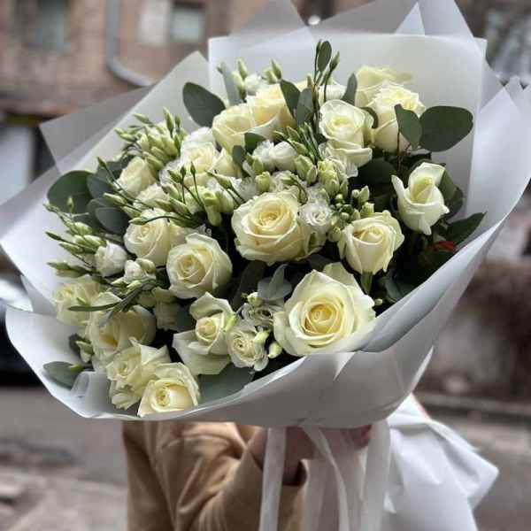 Bouquet of white roses and small white flowers wrapped in white paper