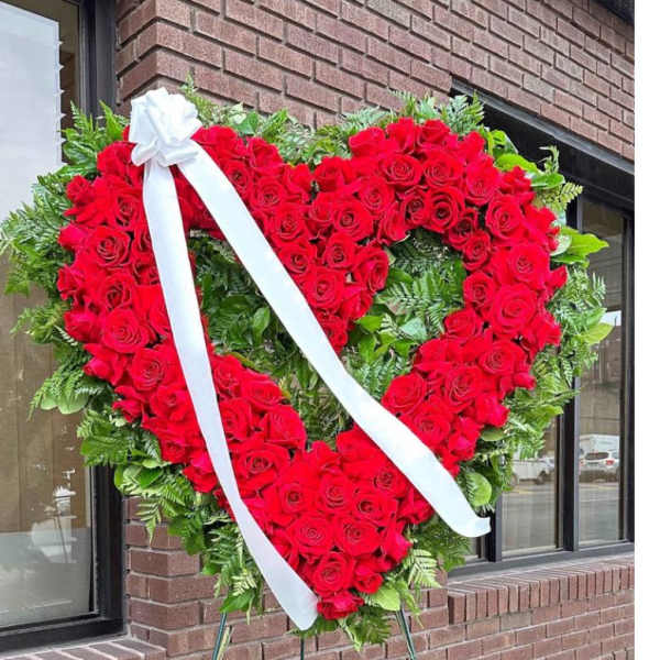 Heart-shaped red rose standing spray with a white ribbon