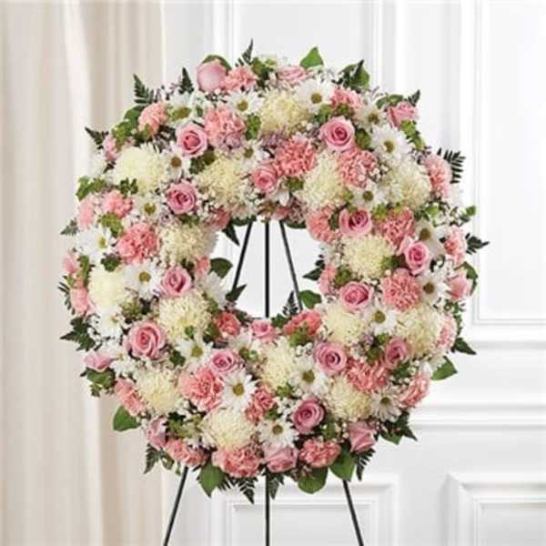 Pink and white floral wreath on a black stand