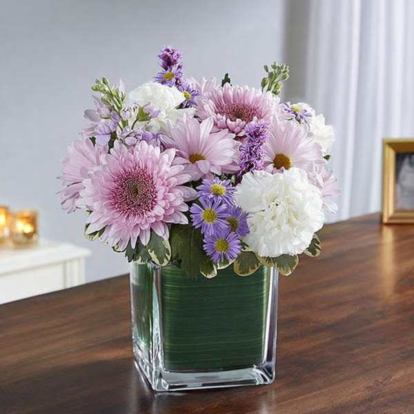 Pink and white flowers arranged in a clear square vase
