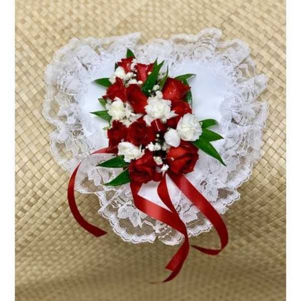 Heart-shaped bouquet of red and white flowers with lace trim and red ribbon