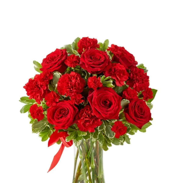Red roses and carnations in a clear glass vase with a red ribbon