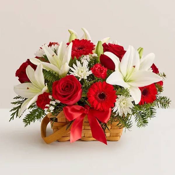 Red and white flower arrangement in a wicker basket with a red ribbon